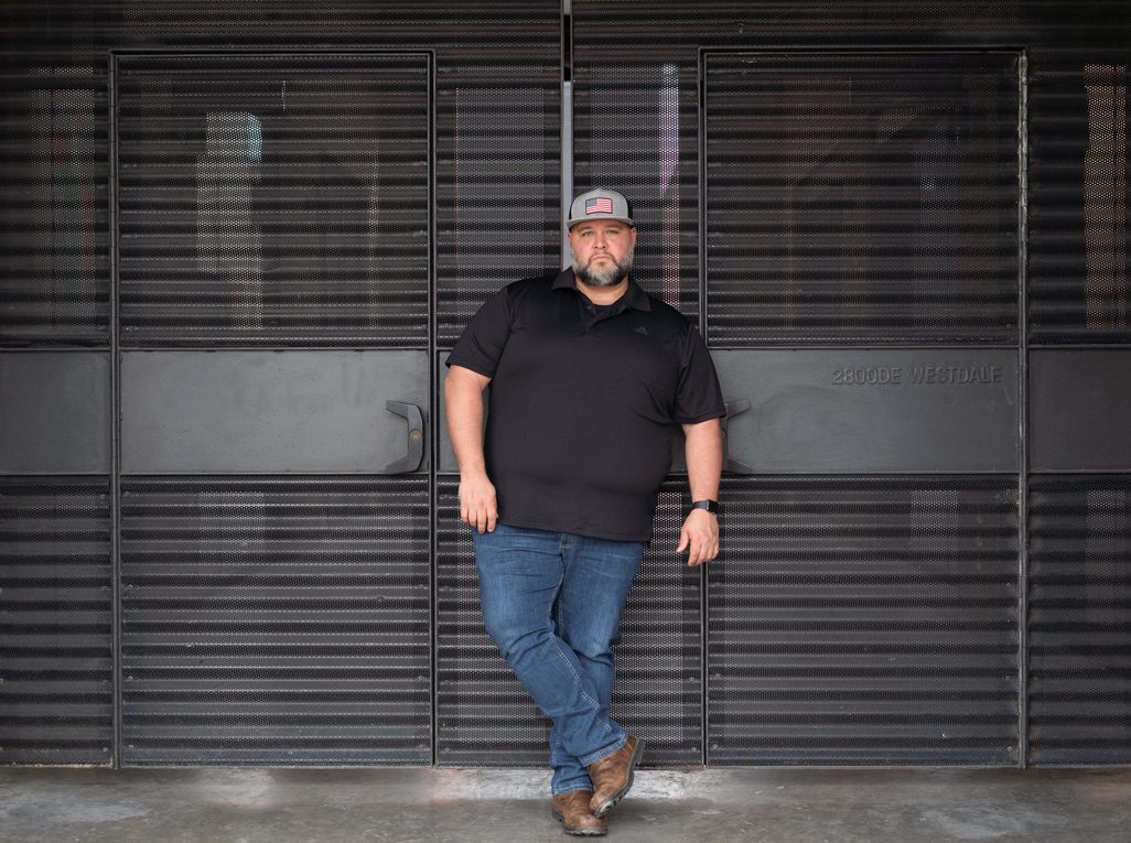 Will Ruggles standing in front of industrial metal doors, looking at the camera