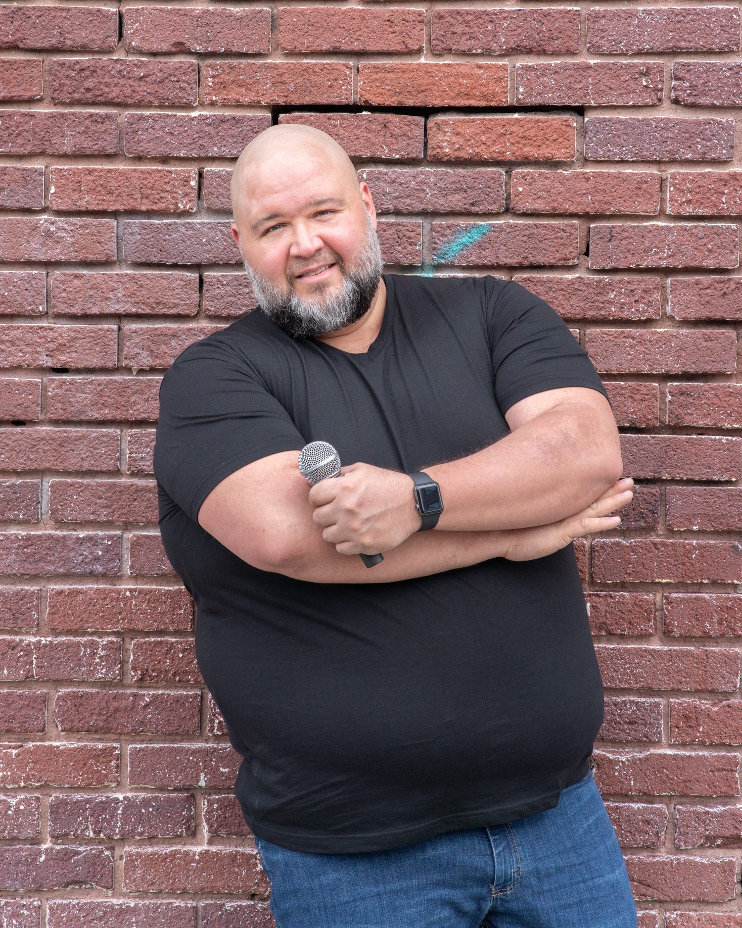 Will Ruggles holding a microphone in front of a brick wall